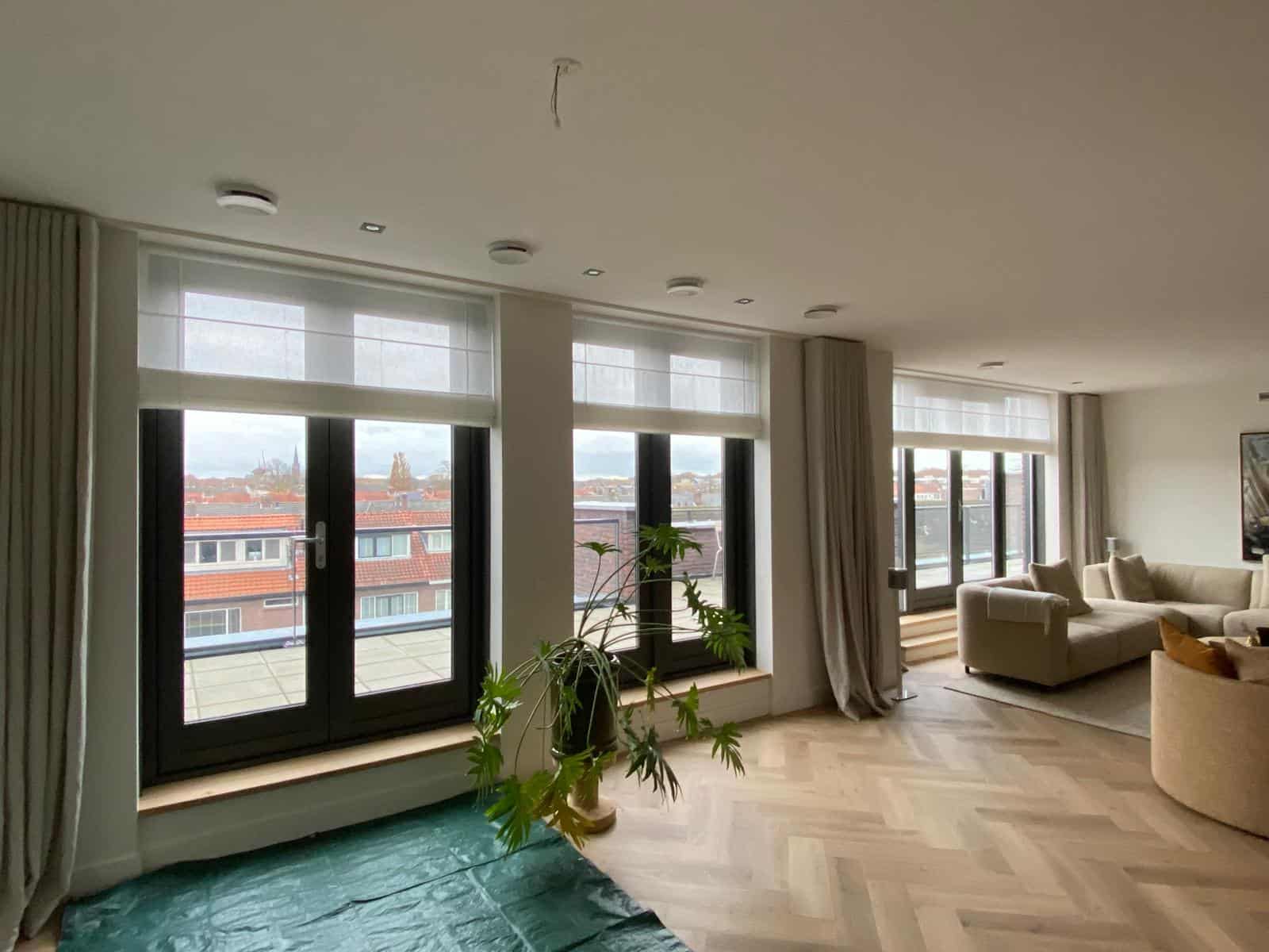 woonkamer met houten visgraatvloer en grote ramen waar onzichtbare UV protectie folie op is aangebracht