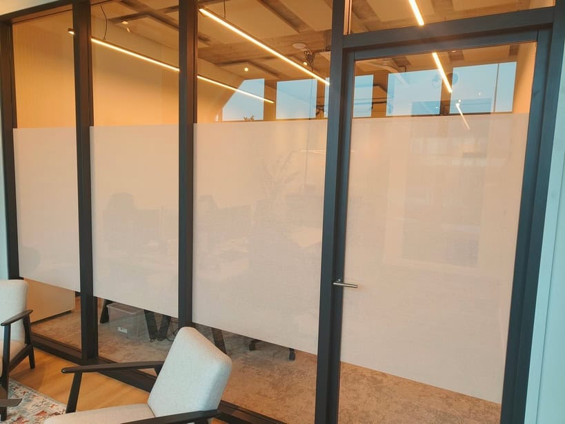 oplus_8388608 Een interieurfoto van drie ramen in een huis, elk voorzien van decoratief glas in de bovenste delen, met een kleurrijk patroon van gele en oranje tinten. Het onderste gedeelte van de ramen heeft matte folie, die privacy biedt terwijl het uitzicht naar buiten behouden blijft. De ramen zijn typisch voor een oud huis, met een klassieke uitstraling door de combinatie van het glas-in-lood boven en het moderne matte folie eronder. In de achtergrond zijn andere huizen zichtbaar.